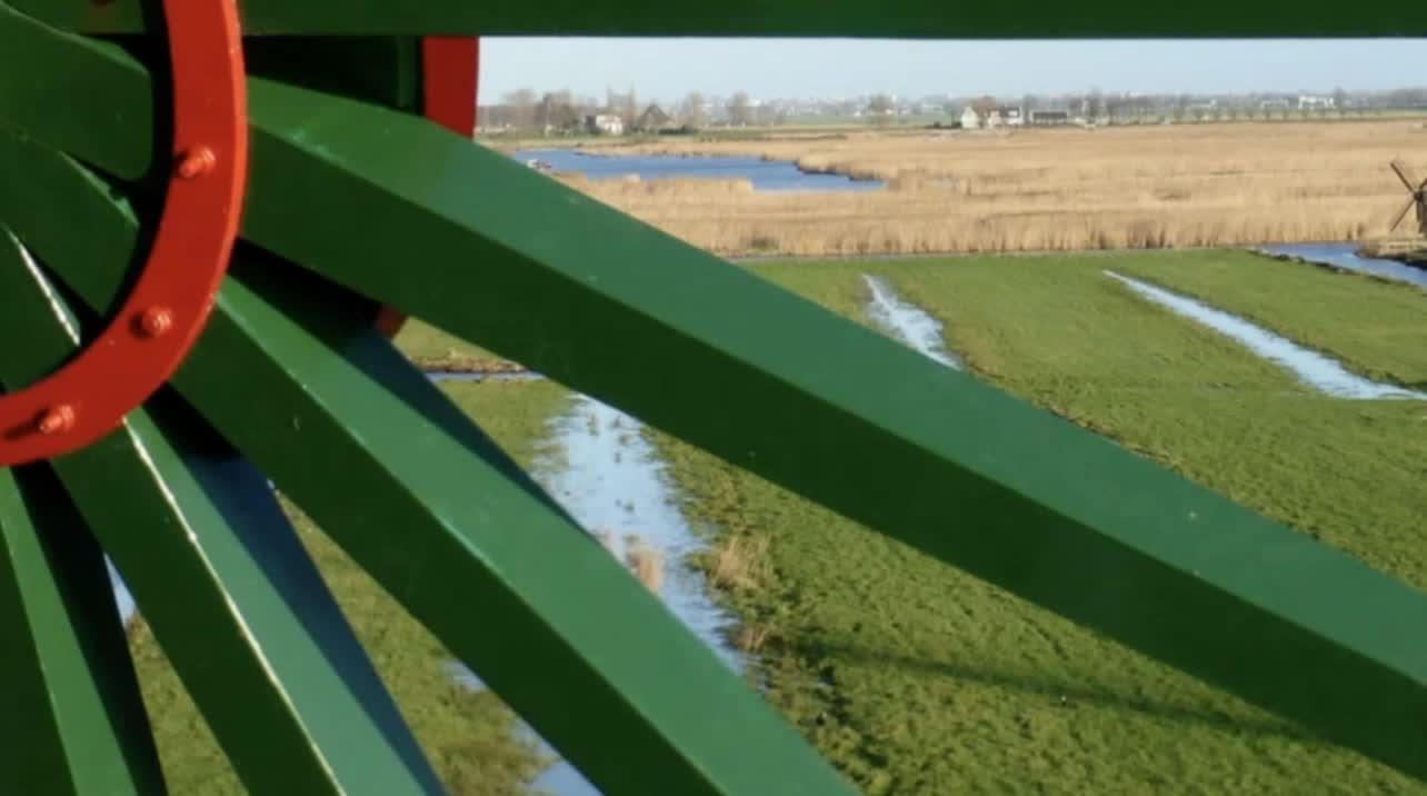 Het groene kruirad met de rode naaf van een molen, met daarachter de Westzaanse polder